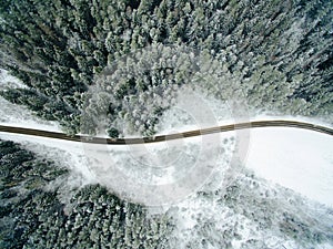 Aerial view of snowy forest with a road.