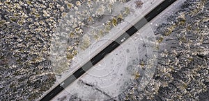 Aerial view of snowy forest with a road and car. Captured from above with a drone