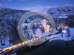 Aerial view of snowy mountains, church, bridge, lights at night