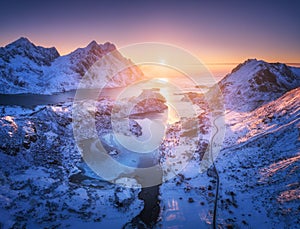 Aerial view of snowy mountains, sea, purple sky at sunset