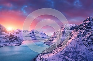 Aerial view of snowy mountains, sea, road, sky with pink clouds