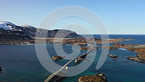 Aerial view of snowy mountains at sunset in Lofoten Islands, Norway. Winter landscape with beautiful road, water, rocks