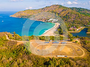 Aerial view of a soccer or football field at Patong beach with blue turquoise seawater, and tropical green forest trees with