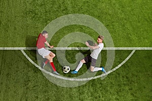 Aerial view of soccer football players in sports uniform and football boots battling for the ball over green grass field