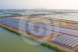 Aerial view of solar panels or solar cells on the roof in farm. Power plant with lake or river, renewable energy source in