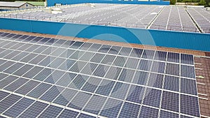 Aerial view of solar power plant with blue photovoltaic panels mounted of industrial building roof.