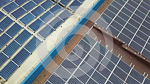 Aerial view of solar power plant with blue photovoltaic panels mounted of industrial building roof.