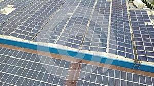 Aerial view of solar power plant with blue photovoltaic panels mounted of industrial building roof.