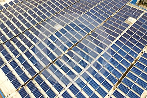 Aerial view of solar power plant with blue photovoltaic panels mounted of industrial building roof