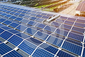 Aerial view of solar power plant with blue photovoltaic panels mounted on industrial building roof for producing green