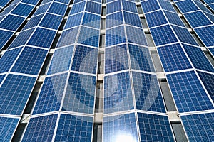 Aerial view of solar power plant with blue photovoltaic panels mounted on industrial building roof for producing green