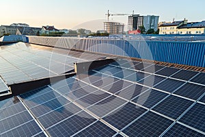 Aerial view of solar power plant with blue photovoltaic panels mounted on industrial building roof for producing green