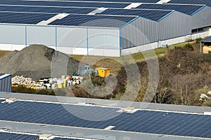 Aerial view of solar power plant with blue photovoltaic panels mounted on industrial building roof for producing green