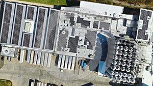 Aerial view of solar power plant with blue photovoltaic panels mounted on industrial building roof for producing green