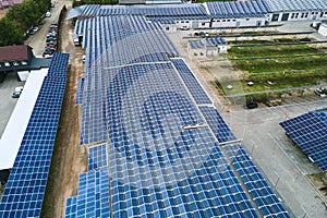 Aerial view of solar power plant with blue photovoltaic panels mounted on industrial building roof for producing green ecological