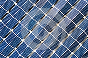 Aerial view of solar power plant with blue photovoltaic panels mounted on industrial building roof for producing green ecological