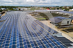 Aerial view of solar power plant with blue photovoltaic panels mounted on industrial building roof for producing green ecological