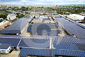 Aerial view of solar power plant with blue photovoltaic panels mounted on industrial building roof for producing green ecological