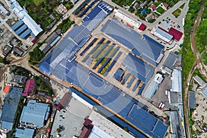 Aerial view of solar power plant with blue photovoltaic panels mounted on industrial building roof for producing green ecological