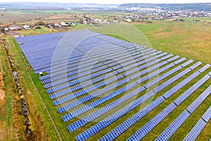 Aerial view of solar power plant on green field. Electric farm with panels for producing clean ecologic energy