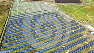 Aerial view of solar power plant under construction on green field. Assembling of electric panels for clean ecologic