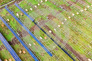 Aerial view of solar power plant under construction on green field. Assembling of electric panels for clean ecologic