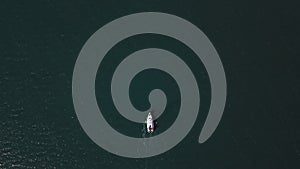 Aerial view of solitary yacht navigating through calm blue ocean waters. Drone shot of luxury boat on serene sea voyage