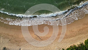 Aerial view of solo female strolling on sandy beach wave edge slow motion. Vacation traveler walks seaside, leaves