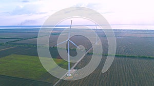 Aerial view of some operating air turbines in a field near the coast