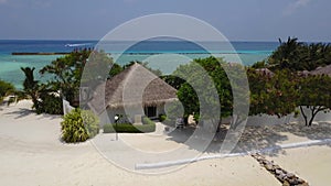Aerial view of spa bungalow on tropical island resort hotel with white sand beach, palm trees and turquoise Indian ocean
