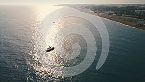 Aerial view speed boat float near the coast in calm water on a sunny day. Sun reflection of the on the water surface.