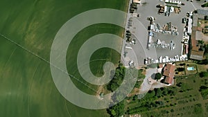 Aerial view, spinning top shot of irrigation system wheat green field, and parking next to it