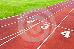 Aerial view of sports stadium with red running tracks with numbers on it and green grass football field