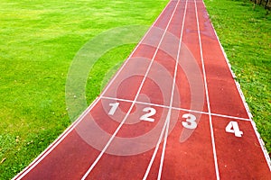 Aerial view of sports stadium with red running tracks with numbers on it and green grass football field