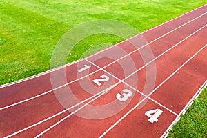 Aerial view of sports stadium with red running tracks with numbers on it and green grass football field