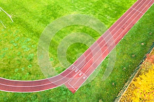 Aerial view of sports stadium with red running tracks with numbers on it and green grass football field