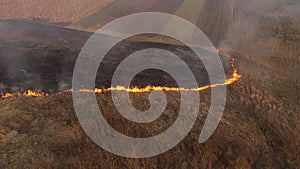 Aerial view of spring dry grass burning field. Fire and smoke in the meadow, nature pollution and danger, shrubs and common waste