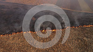 Aerial view of spring dry grass burning field. Fire and smoke in the meadow, nature pollution and danger, shrubs and common waste