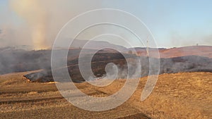 Aerial view of spring dry grass burning field. Fire and smoke in the meadow, nature pollution, shrubs and common waste are burned