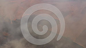 Aerial view of spring dry grass burning field. Fire and smoke in the meadow, nature pollution, shrubs and common waste are burned