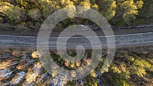 Aerial view of spring rural road in yellow pine forest with snow in rural Russia