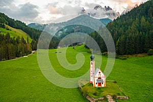 Aerial view of St. Johann chapel in South Tyrol against the Dolomites covered by clouds