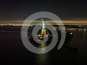 Aerial view of the Statue of Liberty at night with the lights of New Jersey in the background