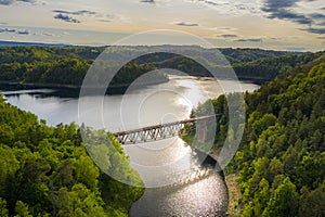 Aerial view of steel underspanned suspension railway bridge over Bobr River in Pilchowice, beautiful lake