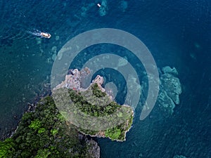 Aerial view of a steep cliff and a motor boat. Jagged coast on the Adriatic Sea. Cliffs overlooking the transparent sea.