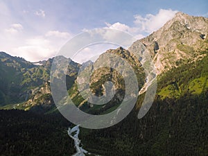 Aerial view of the stormy flow of the Dolra River, in the middle of a forest and high Caucasian mountains. way to Ushba mount, a