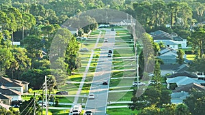 Aerial view of street traffic with driving cars in small town. American suburban landscape with private homes between