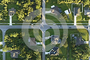 Aerial view of street traffic with driving cars in small town. American suburban landscape with private homes between