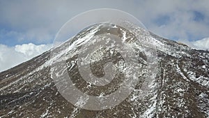 Aerial view of the summit of the Teide volcano on Tenerife, covered with snow and clouds.