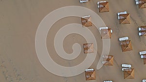 Aerial view sun loungers and straw parasols on seashore. No people morning beach